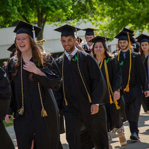 Image displays students walking proudly to graduate from MU